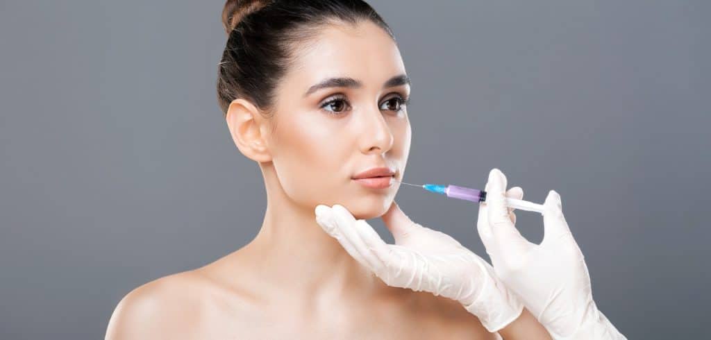 woman is receiving a dermal filler injection administered by a professional