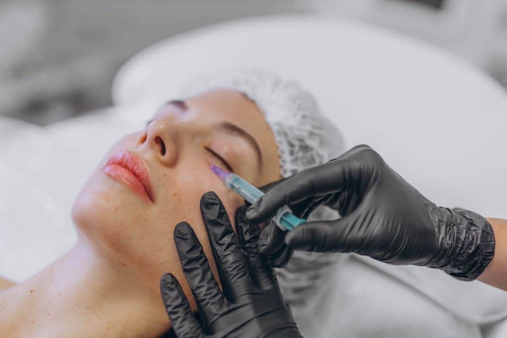 professional beautician injects Botox into the face of a young woman