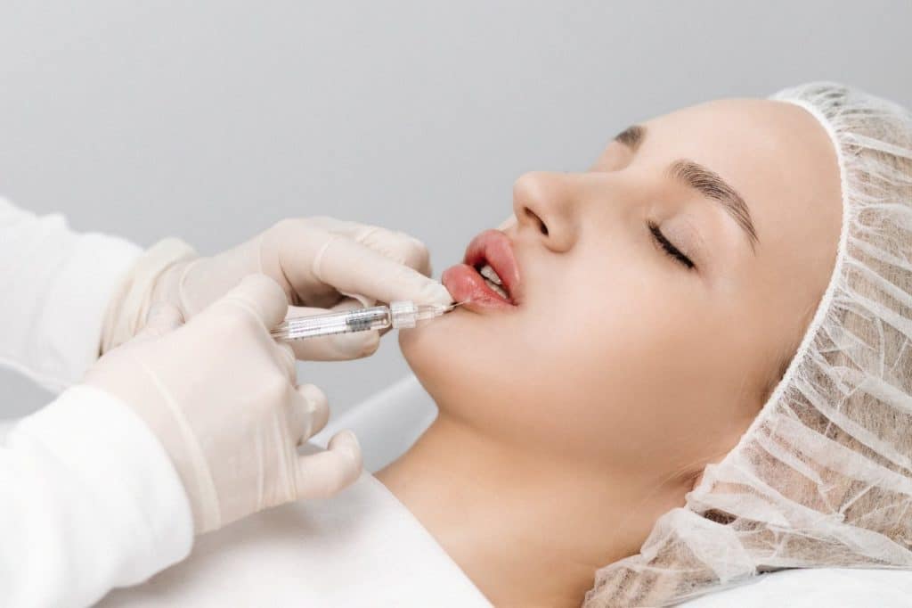 certified aesthetic professional injecting patient's lower lip