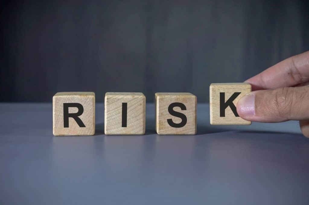 Hand holding wooden block with risk word