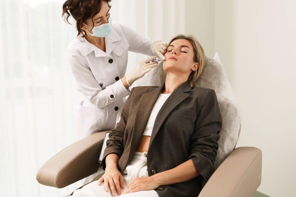 Doctor and client during lip augmentation filler injections in aesthetic medical clinic