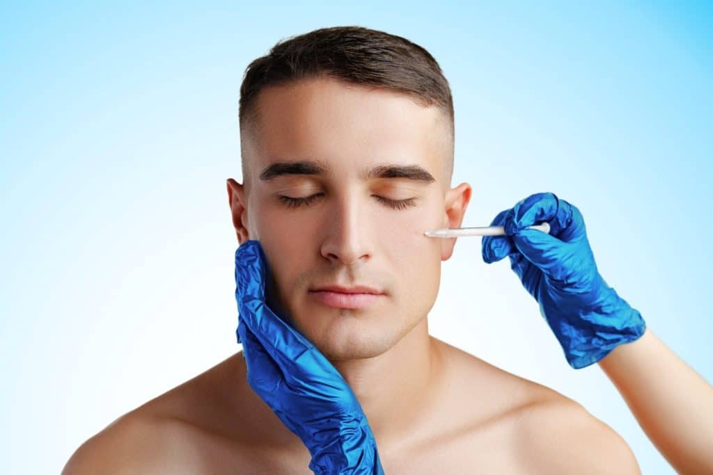 expert aesthetician injecting a young man's face