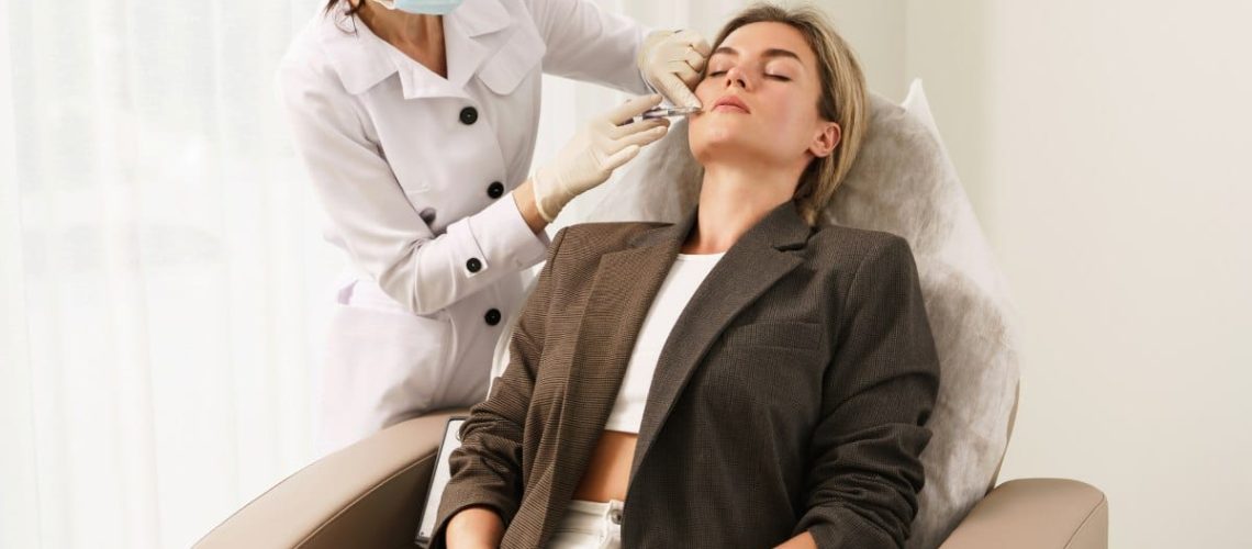 Doctor and client during lip augmentation filler injections in aesthetic medical clinic