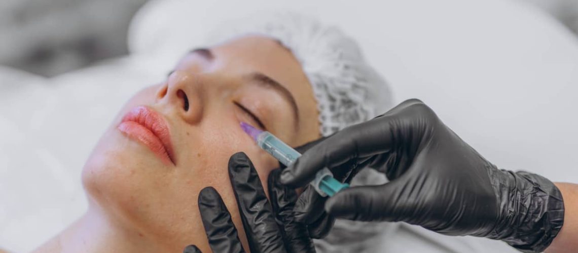 professional beautician injects Botox into the face of a young woman